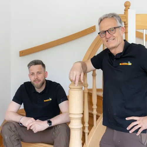 Markus Kaymer sitzt links auf einer Treppe. Rechts neben der Treppe steht Klaus Herold.
